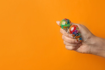 Fototapeta na wymiar Woman squeezing colorful slime on orange background, closeup. Antistress toy