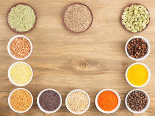 Buckwheat, oat, millet, green cardamom, allspice, cumin, pepper chili, fenugreek, turmeric, cloves, masala, mustard seeds on brown wooden background. Indian cuisine, ayurveda, naturopathy concept