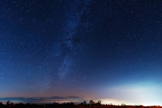 A magical starry night on the river bank with a milky way in the sky and falling stars in the winter.
