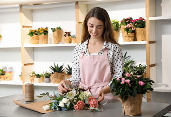 Florist making bouquet with fresh flowers at table in shop