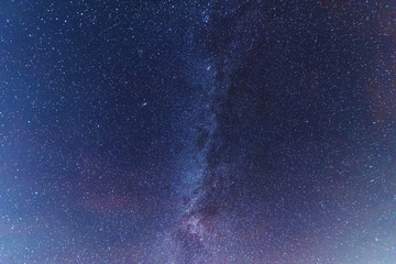 A magical starry night on the river bank with a milky way in the sky and falling stars in the...