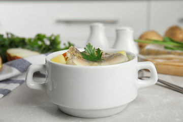 Delicious fish soup in bowl on light table, closeup