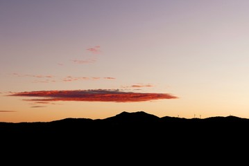 Paisaje al atardecer de una montaña y sus molinos de viento 