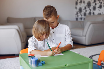 Brother and sister in a playing room. Children drawing at the table