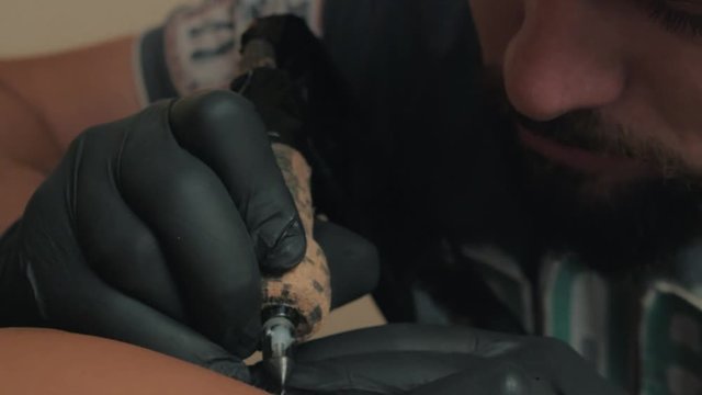 Professional tattoo artist concentrates at work, close up in  slow motion