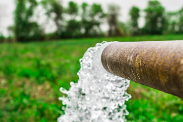 Obraz premium high pressure crystal bluish sweet water flushing out of an agriculture industrial tube waell in fields 