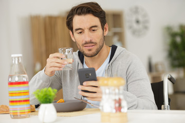 handicapped man looking at smartphone while eating his meal