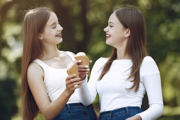 Beautiful girls in a jeans skirts. Women in a summer park. Friends with ice cream