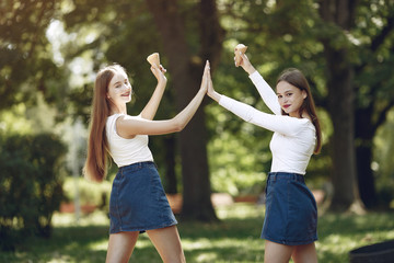 Beautiful girls in a jeans skirts. Women in a summer park. Friends with ice cream