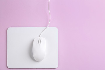 Modern wired optical mouse and pad on lilac background, top view. Space for text