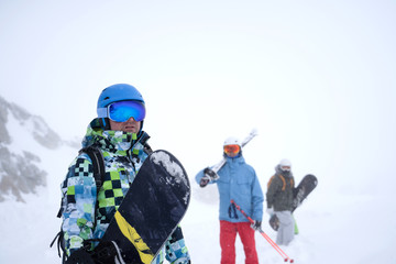 Fototapeta na wymiar Photo of three sports people with skis and snowboard walking through winter resort