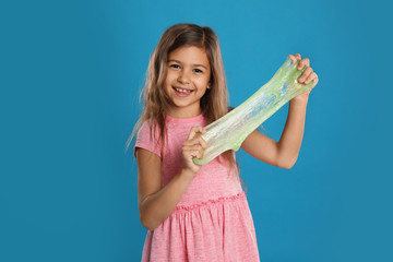 Little girl with slime on blue background