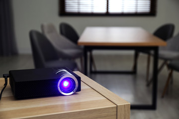 Modern video projector on wooden table in conference room. Space for text