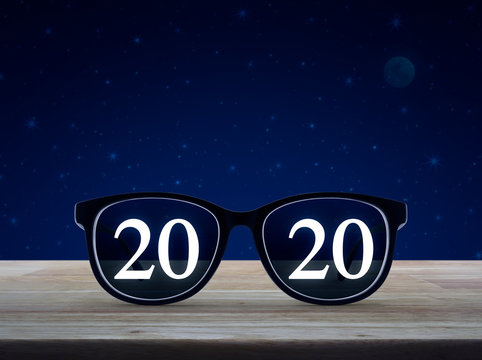 2020 white text with black eye glasses on wooden table over fantasy night sky and moon, Business vision happy new year 2020 concept