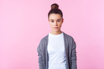 Portrait of cute brunette teenage girl with bun hairstyle in casual pullover and T-shirt looking...