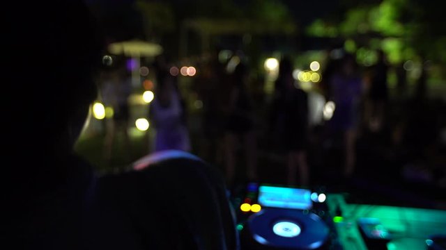 Dancing DJ playing music in front of small crowd, slow motion