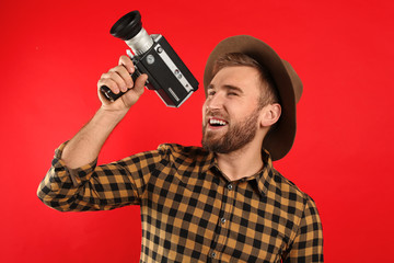 Fototapeta na wymiar Young man with vintage video camera on red background