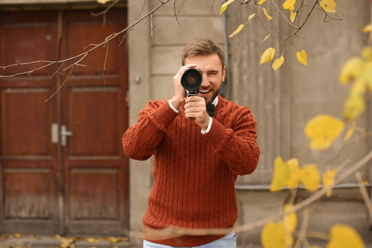 Young man using vintage video camera outdoors - Powered by Adobe