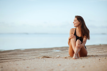 Naklejka premium Wesoła opalona kobieta w bikini na plaży. Piękna młoda kobieta korzystających z dnia na plaży oceanu