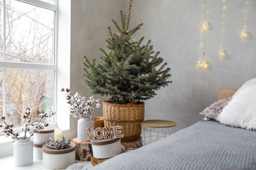 Little Christmas tree with fairy lights in bedroom interior