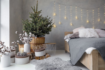 Little Christmas tree with fairy lights in bedroom interior