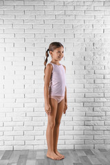 Cute little girl in underwear near white brick wall