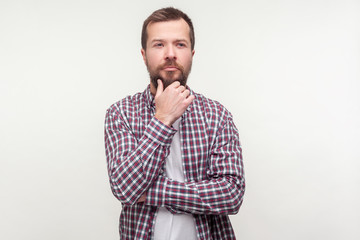Obraz premium Let's think! Portrait of pensive bearded man in plaid shirt touching his chin pondering serious idea, making difficult decision with doubtful thoughtful face. studio shot isolated on white background