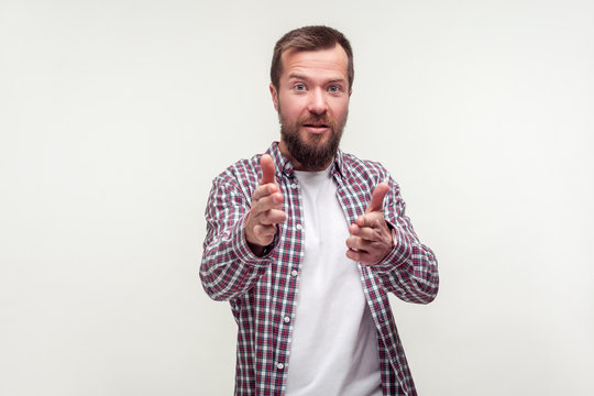 Portrait of young bearded man in casual plaid shirt pointing at camera finger guns with positive face expression, pretending to shoot kill, threat. indoor studio shot isolated on white background
