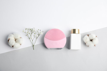 Flat lay composition with face cleansing brush on color background. Cosmetic accessory