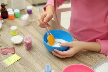 Obraz na płótnie Canvas Little girl mixing ingredients with silicone spatula at table, closeup. DIY slime toy