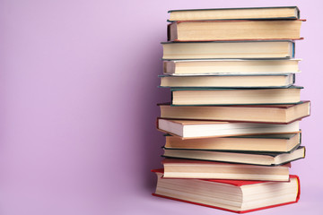 Stack of hardcover books on violet background. Space for text