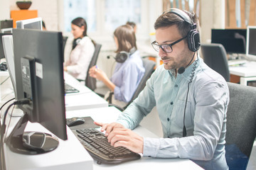 Handsome business man with headphones working in call-centre