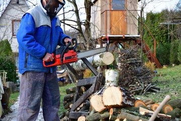 Sawing wood with chainsaw with safety glasses and helmet