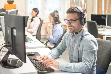 Confident male customer service representative with headset in call center