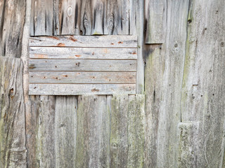 old grey wooden wall with horizontal and vertical planks and rusty nails. natural textured background