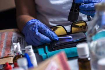 Police specialist examines wallet to collate DNA in a crime scene, conceptual image