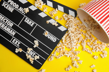 Tasty pop corn and clapboard on yellow background, flat lay
