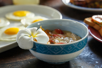 plate with flowers on the edge close-up, porridge with fruit, healthy food, Breakfast on a wooden table, scrambled eggs and fruit sandwiches in background