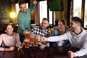 Group of friends celebrating victory of favorite football team in sport bar