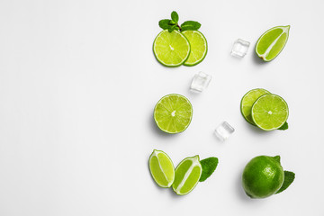 Flat lay composition with fresh juicy limes, mint and ice cubes on white background
