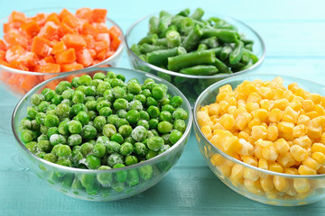 Different tasty frozen vegetables on light blue wooden table