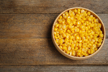 Delicious canned corn on wooden table, top view. Space for text