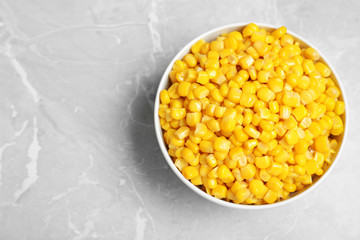 Delicious canned corn in bowl on marble table, top view. Space for text
