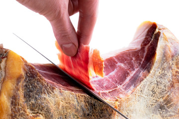 Professional cutter hand carving slices from a whole bone serrano jamon. Knife cutting a spanish...