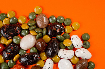 Pebble-dragee with apricots, chocolate, mandarin and marzipan. Tasty, bright, shot on an orange background.