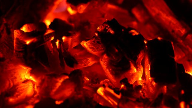 Red smouldering embers burnt in fire. Wind waving smoke. UHD