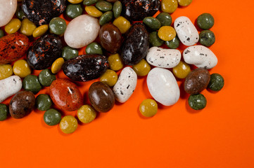 Pebble-dragee with apricots, chocolate, mandarin and marzipan. Tasty, bright, shot on an orange background.