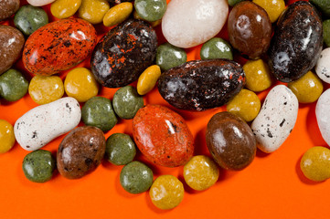 Pebble-dragee with apricots, chocolate, mandarin and marzipan. Tasty, bright, shot on an orange background.