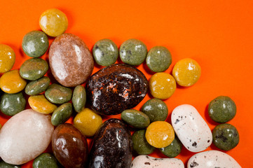 Pebble-dragee with apricots, chocolate, mandarin and marzipan. Tasty, bright, shot on an orange background.