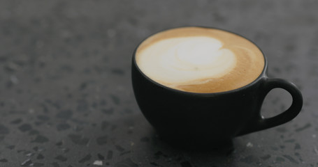 cappuccino in black cup on terrazzo countertop